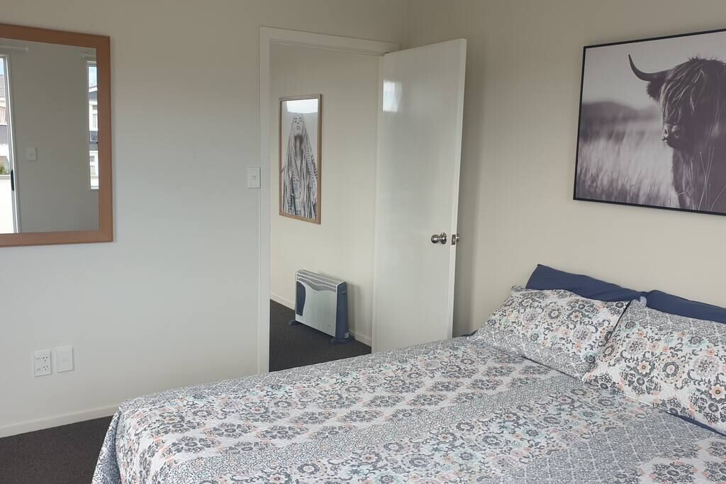 Une chambre à coucher avec un lit, un radiateur, une porte et un tableau encadré au mur.