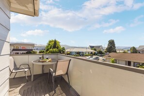 A balcony with a table and chairs, overlooking a residential area with houses and mountains in the background. - ☀️Centre of town☀️Close to Abel Tasman☀️☀️, Pet Fee (Motueka)