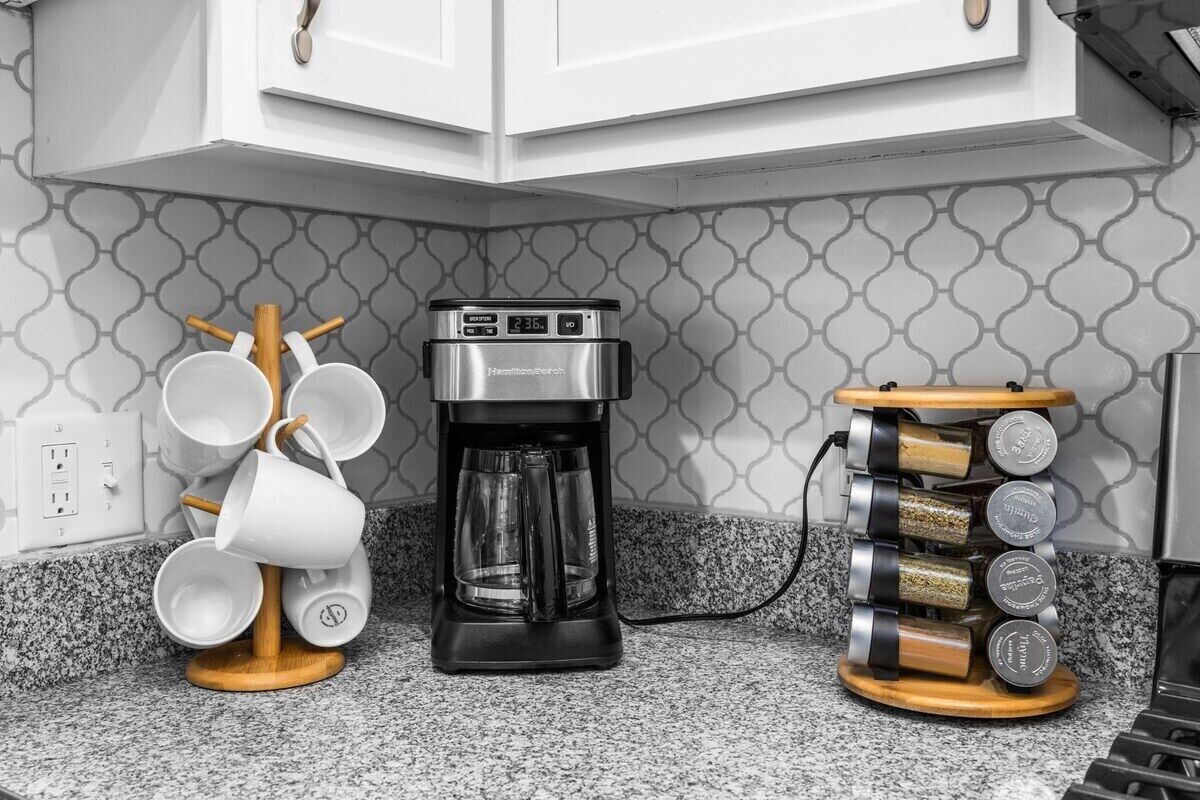Une cuisine équipée d’une machine à café, d’un porte-tasses et d’un étagère à épices.