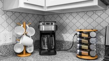 Une cuisine équipée d’une machine à café, d’un porte-tasses et d’un étagère à épices.