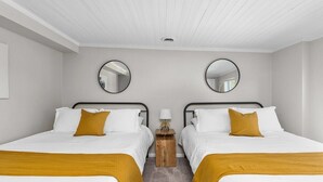 A hotel room with two beds, a small wooden nightstand, and two round mirrors on the walls.