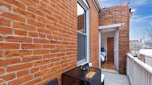 A brick exterior with a glass door leading to a balcony with a table and chairs. - Classic Soulard 2BD King Master & Private Deck (St. Louis)