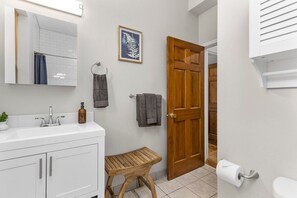 Un baño con lavamanos blanco, espejo y puerta de madera.