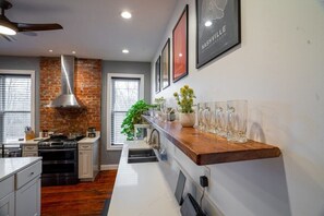 A modern kitchen with a brick accent wall, stainless steel appliances, and a wooden countertop.