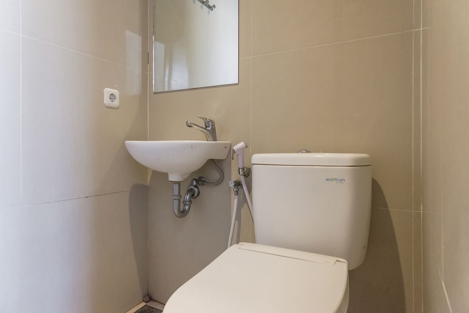 Un baño con un lavamanos blanco, un inodoro y un espejo en la pared.
