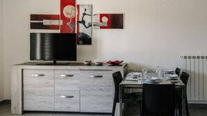 Ein moderner Essbereich mit einem Holzschrank, einem Flachbildfernseher und abstrakter Wandkunst.