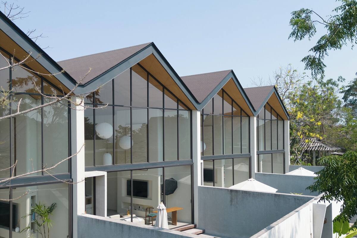 A modern house with large windows, a swimming pool, and a garden area.