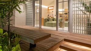 Una casa moderna con terraza de madera, puertas de cristal amplias e iluminación interior.