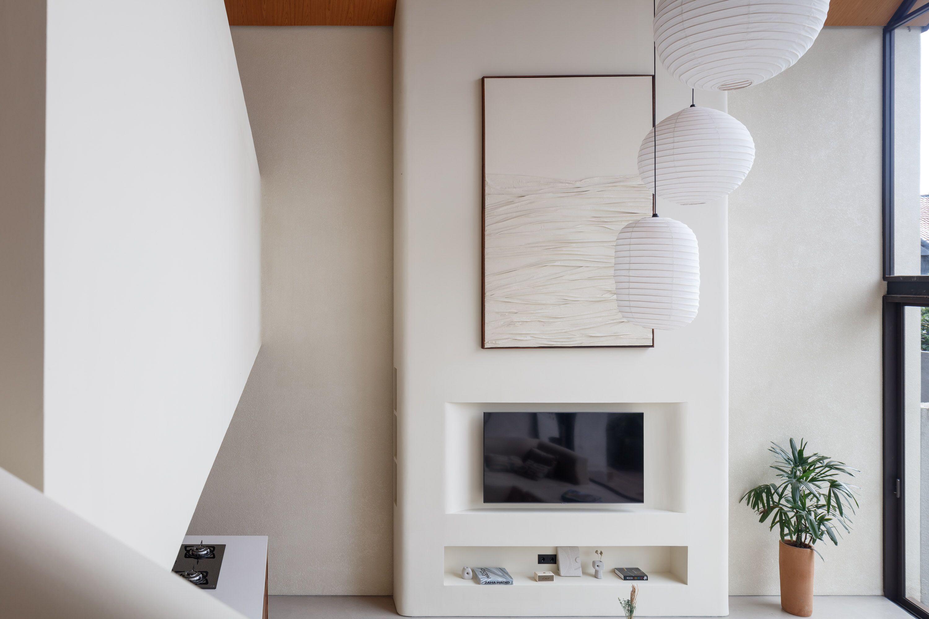 A modern living room with a flat-screen TV, white decorative panels, and hanging paper lanterns.