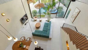 Un interior moderno con zona de comedor, un sofá verde y una escalera.