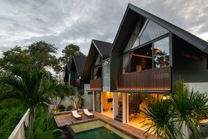 Une maison moderne avec une piscine, de grandes fenêtres et un balcon.