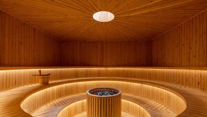 Una sauna de madera con un hogar central y bancos curvos.
