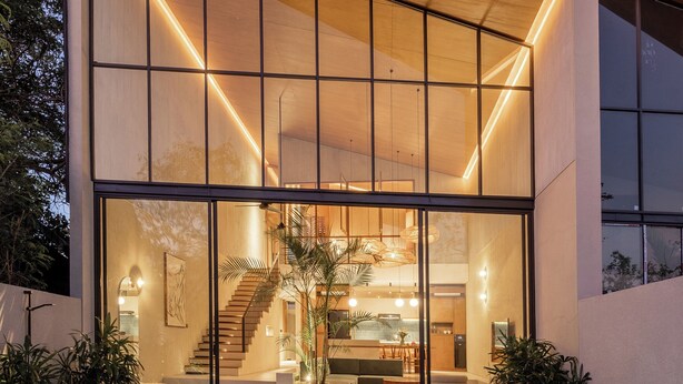 Una casa moderna con piscina, ventanas amplias y una escalera que lleva al interior.