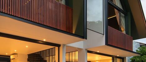 A modern two-story house with a balcony, a staircase, and a pool area.