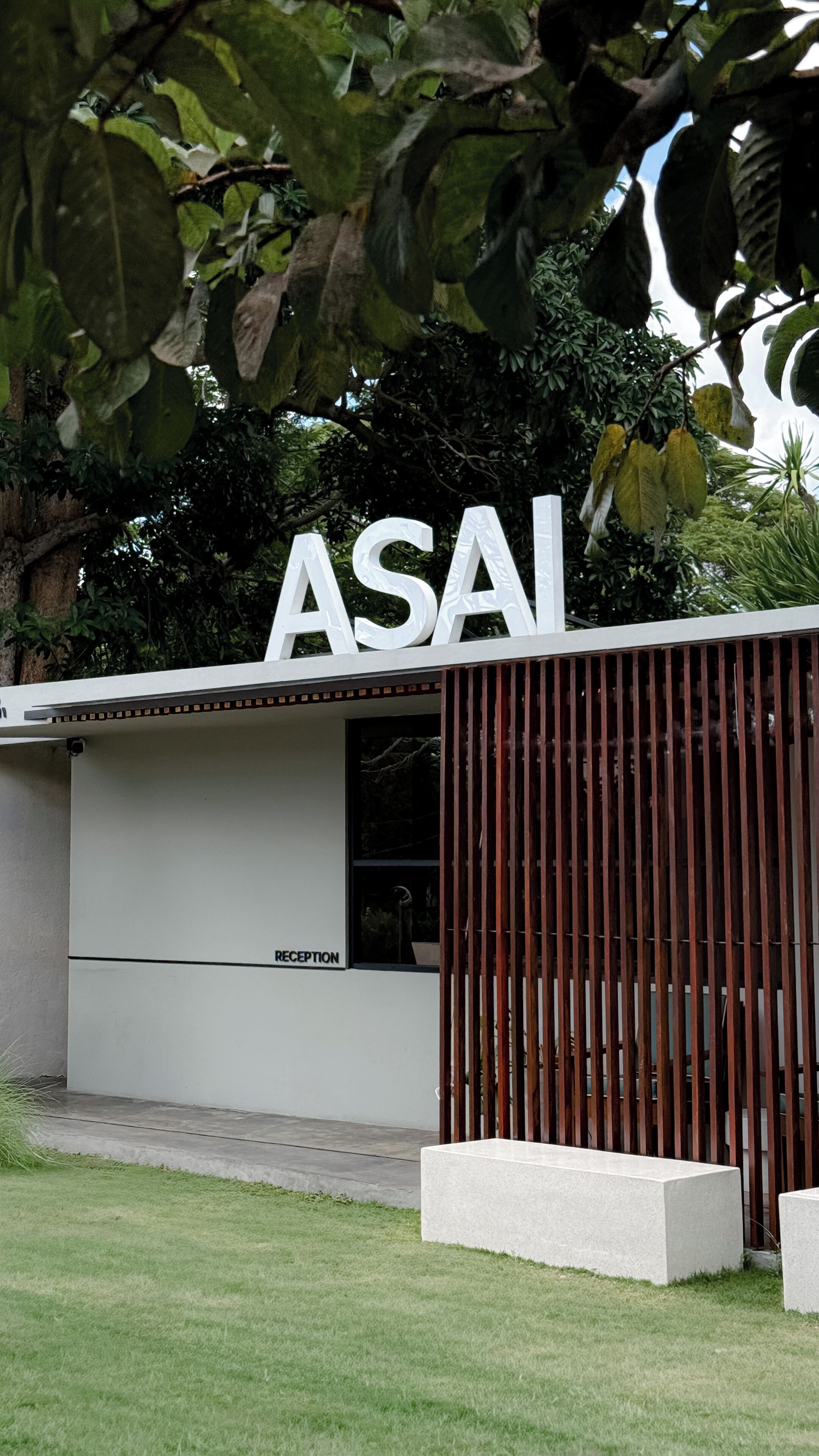 Ein Gebäude mit einem großen 'ASAI'-Schild, einer Rezeption und einem modernen Design mit einer Holzlamellenstruktur.