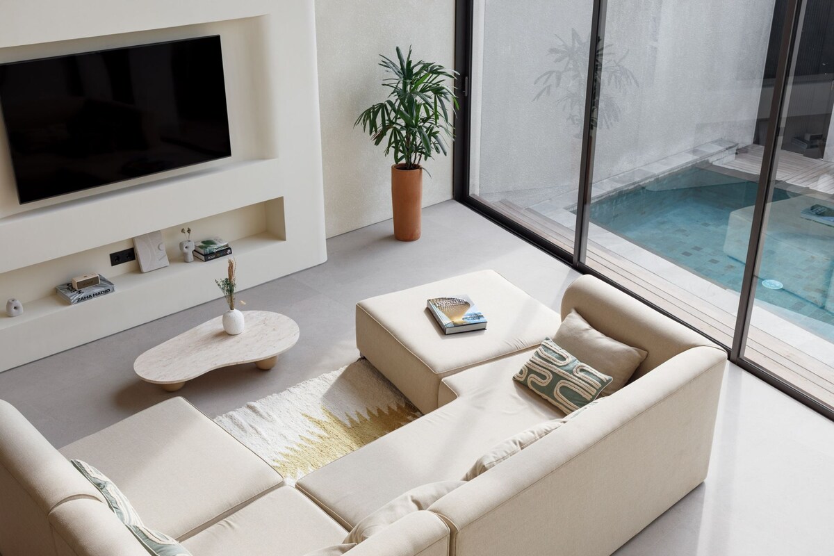 Una sala de estar moderna con un televisor de pantalla plana grande, un sofá, una mesa de centro y una planta en maceta.