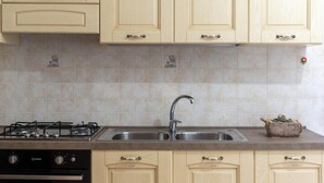 Une cuisine avec des meubles de couleur beige, un évier en acier inoxydable et une cuisinière à gaz.