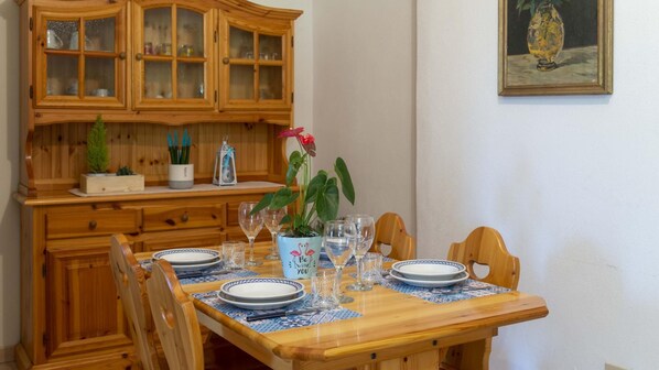 Une table à manger en bois, mise avec des assiettes, des verres et une plante décorative.