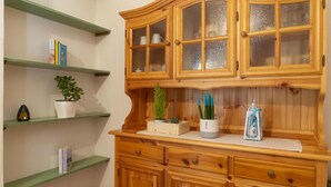 Un meuble en bois avec des portes en verre, une étagère verte et un vase blanc contenant une plante.