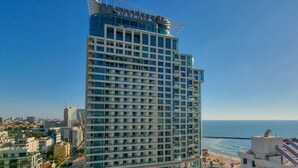 Een hoog hotel met een modern ontwerp, met een opvallende glazen gevel en meerdere balkons.