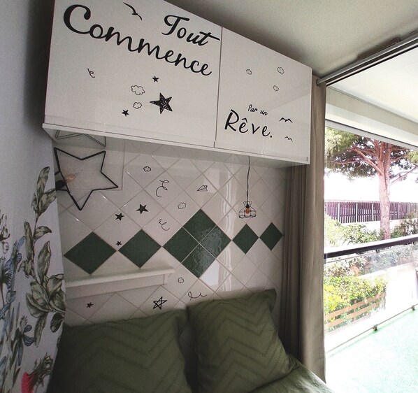 Una habitación con cama, una pared con azulejos decorativos y una ventana con vistas al exterior.