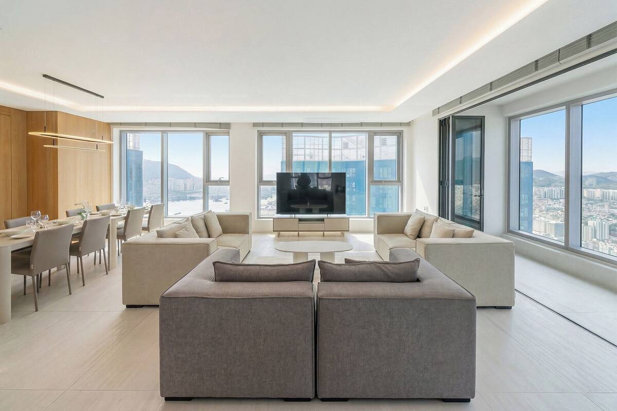 Uma sala de estar moderna com um amplo sofá, uma área de jantar e uma televisão.