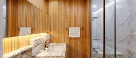 A modern bathroom with wooden paneling, a marble sink, and a glass-enclosed shower.