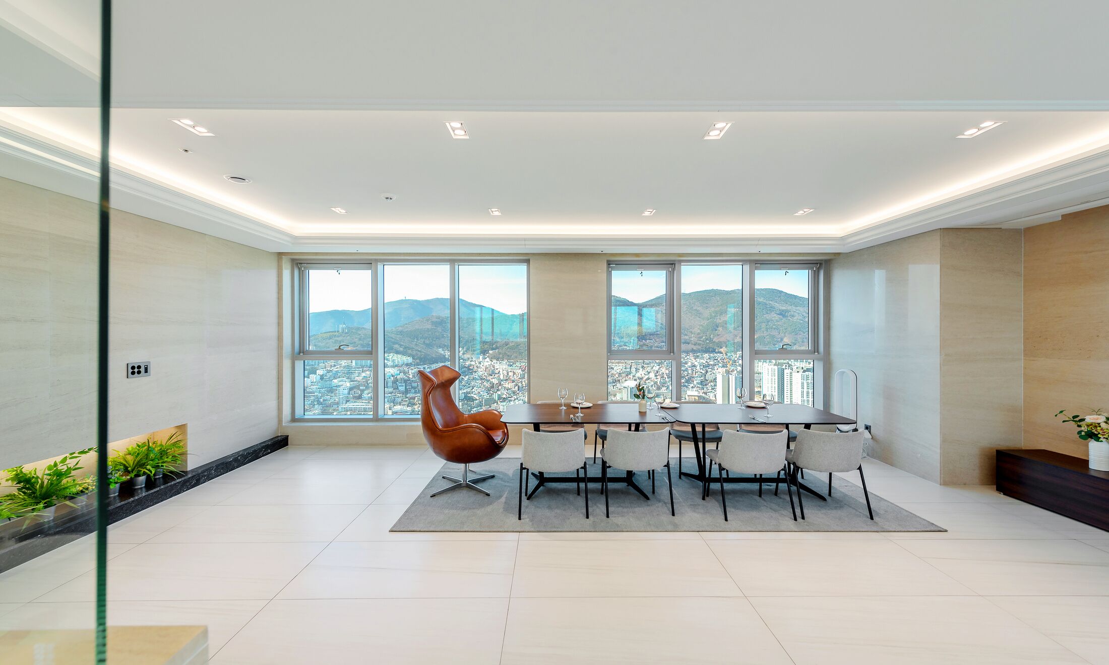 A modern dining area with a panoramic city view, a large window, and a unique chair design.