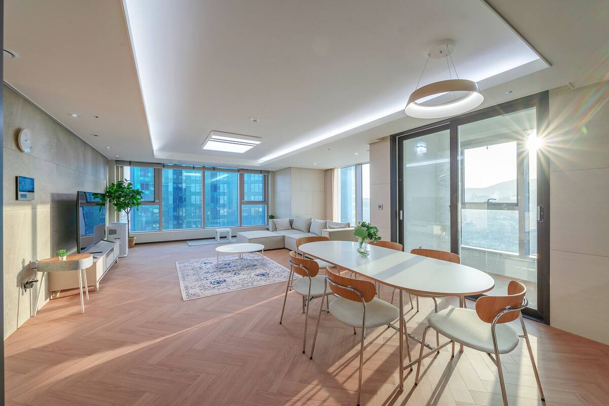 Quarto moderno e bem iluminado com uma grande mesa de jantar, assentos confortáveis e amplas janelas com vista para a cidade.