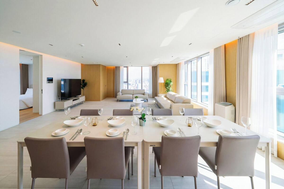 Quarto de hotel moderno com área de refeições, sala de estar e televisão.