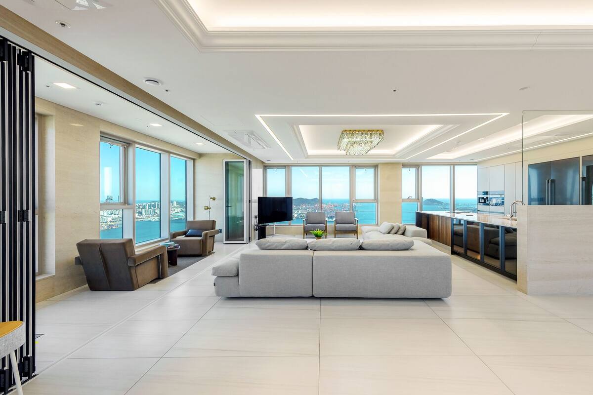 Uma sala de estar moderna com um sofá grande, uma TV e um espaço de refeições com cozinha.