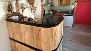 Una cocina con una isla de madera, armarios de madera y una pared destacada en rojo.