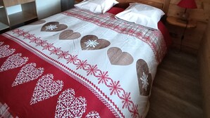 Un dormitorio con cabecera de madera, una decoración con forma de corazón y una cama con colcha de cuadros rojos y blancos.