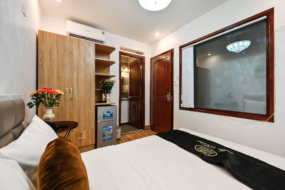 Habitación de hotel con cama, escritorio, armario, kitchenette pequeña y ventana con vistas.