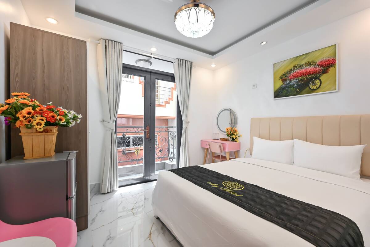 Habitación de hotel moderna con cama, escritorio, silla, tocador y un ventanal con cortinas.