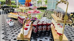 A table with various desserts and drinks, including cupcakes, canisters, and tiered dessert stands. - Beijing Jiuxian Apartment (Beijing)