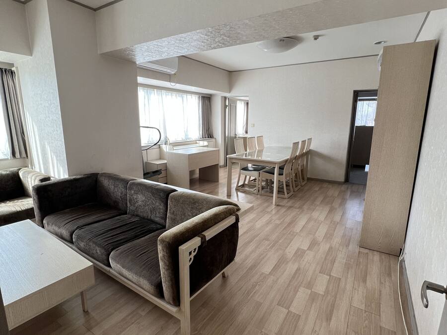 A spacious living area with a sofa, a dining table, and chairs.