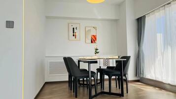 Un comedor con una mesa dispuesta para cuatro, una lámpara colgante y dos obras de arte enmarcadas en la pared.