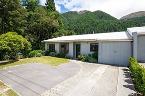 Uma casa térrea com calçada pavimentada, pequeno jardim frontal e garagem.