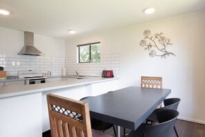 Uma cozinha moderna com azulejos brancos, uma ilha central, uma torradeira vermelha e um painel decorativo na parede.