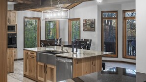 Una cocina amplia con una isla grande, armarios de madera y una lámpara colgante moderna.