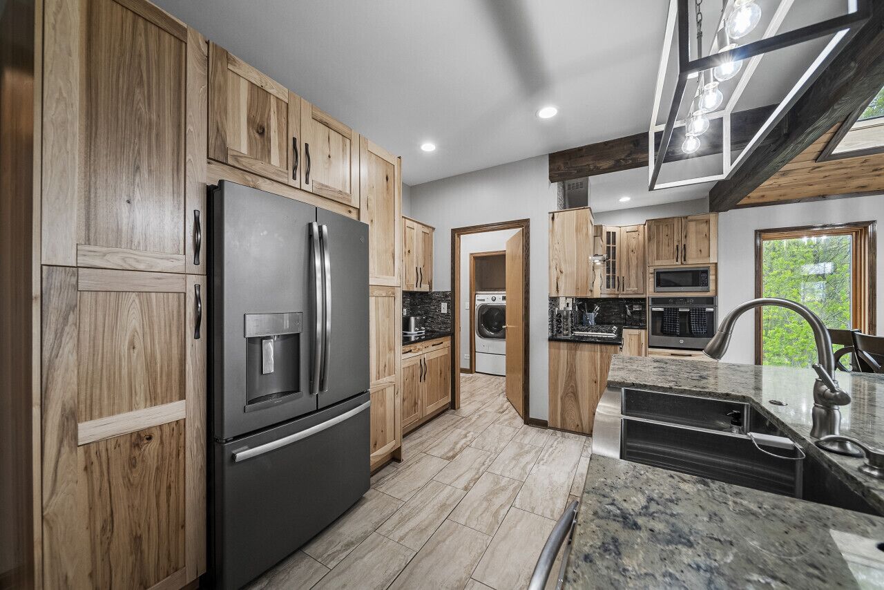 A modern kitchen with wooden cabinets, stainless steel appliances, and a granite countertop.