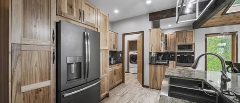 A modern kitchen with wooden cabinets, stainless steel appliances, and a granite countertop.