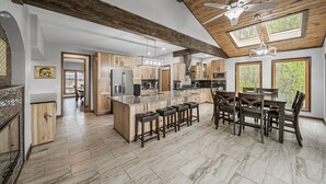 Una cocina amplia con vigas de madera, una isla grande con taburetes y un comedor con mesa y sillas.