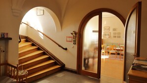 A staircase with wooden steps and a wooden handrail, leading to a room with a door that has a frosted glass panel. - Birgittasystrarnas Gästhem (Vadstena)