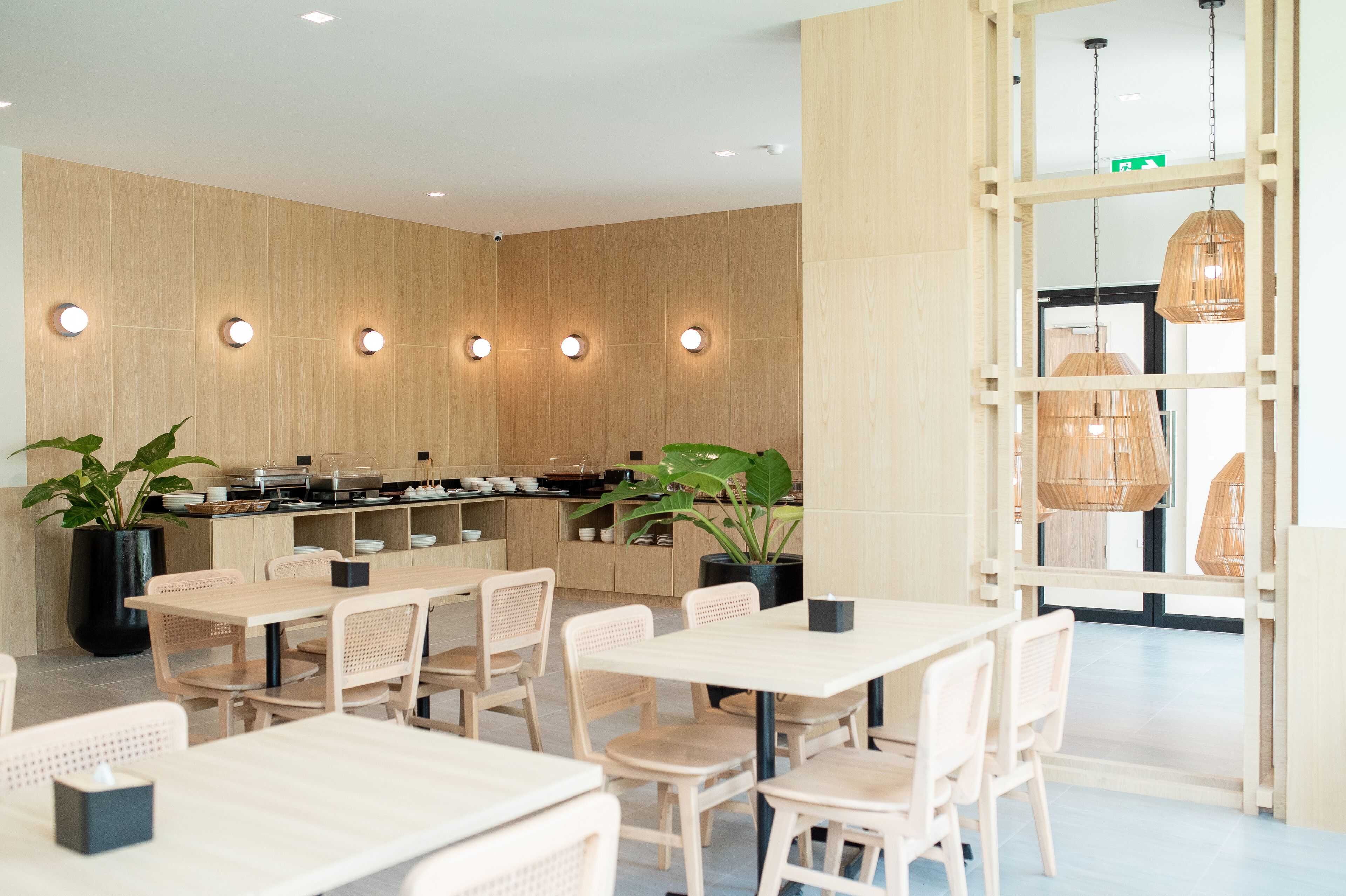 Un restaurante moderno con paredes de madera, luces de techo redondas y lámparas de bambú colgantes.