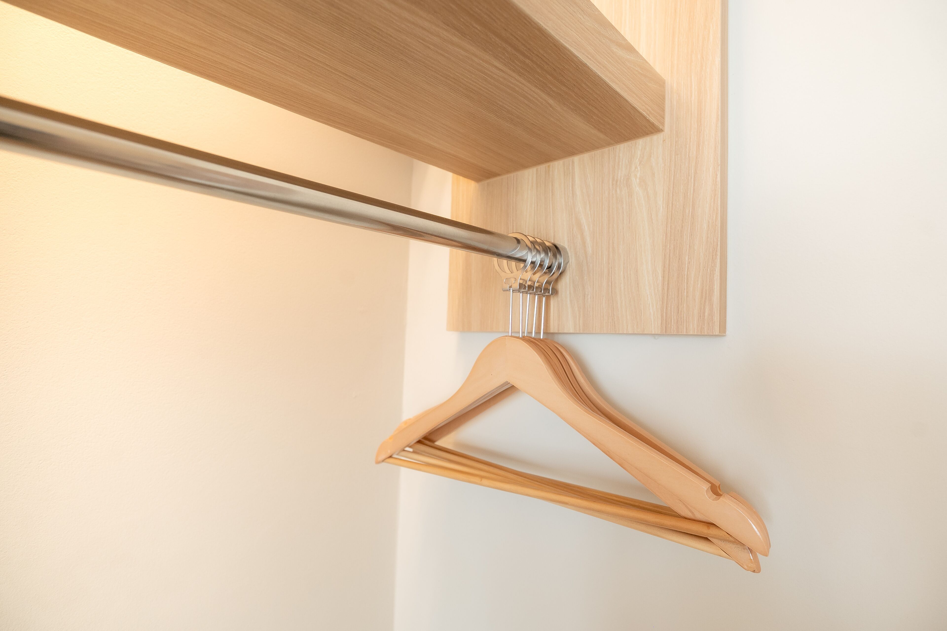 A wooden hanger on a metal rod against a wooden wall.