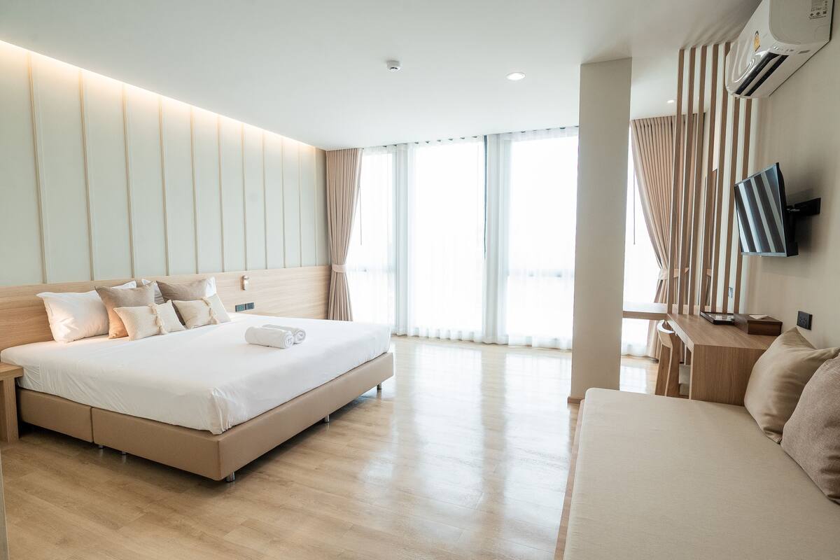 Una camera d'albergo moderna con un letto grande, un divano, una TV e una scrivania.