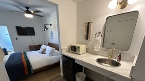 Ein Hotelzimmer mit Bett, Mikrowelle, Spüle und Deckenventilator.