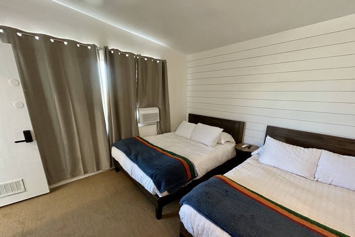Ein Hotelzimmer mit zwei Betten, einem Heizkörper und einem Fenster mit Vorhängen.